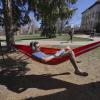 Student lounging in hammock reading on campus