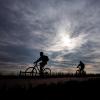 Silhouette of two people biking to work