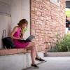 Campus community member works on laptop while sitting outside
