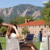 person sitting outside on campus working on laptop