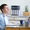 Man rubs back while sitting at desk
