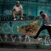 Boys skateboarding by a graffiti wall