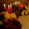 Table with red, green and black candles; fresh fruit and wrapped presents