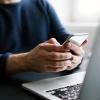 person checking phone and sitting near laptop