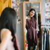 Person holding up a dress and looking in a mirror
