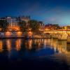 Pont Neuf bridge and Cite island over Seine river at night in Paris