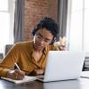 person writing in notebook during a webinar