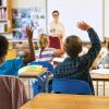 young students raising their hands in class