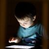 Little boy using tablet device at nighttime