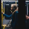 Woman stands during a dark bus ride