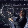 Professor Albert Bartlett holds up bicycle wheel in classroom