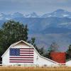 White barn with painted American flag sits in front of the Rockies
