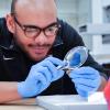 Student examines ancient coin under a magnifying glass