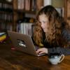 person sits at computer with cup of coffee