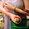 Woman puts red apple into her grocery shopping basket