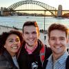 Three students take a photo by the Harbour Bridge in Sydney, Australia