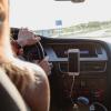 person driving in car with smartphone docked on dashboard
