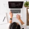 person on laptop with notebook nearby