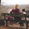 Adult sits with two kids on a park bench