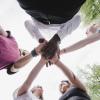 Students stand in circle with hands together at center
