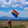 A pride flag in front of the Rocky Mountans