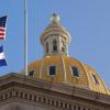 The American flag and the Colorado flag blowing in front of the state capitol dome.