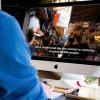 Man watches video with captions on iMac computer