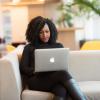 Woman on laptop sits on a couch