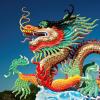 A colorful Chinese dragon sculpture with a bright blue sky in the background.