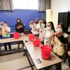Young students dip their hands into buckets of frigid ice water