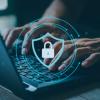 person on laptop with security lock and shield graphic overlay