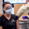 A nurse gives a woman a vaccine shot in the shoulder.