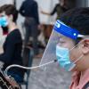 Student plays a musical instrument with a mask and a face shield on.