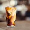 Cream swirls around a glass of iced coffee