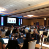 A large audience of people sit at tables during Destination Startup.