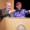 Chancellor Phil DiStefano and Professor Reiland Rabaka, smiling, point to the crowd from a podium