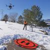Members of the GEER team watch a drone take off from a snowy driveway