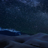 Stars in the night sky above sand dunes