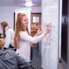 Student writes on a white board in the classroom