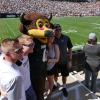 Family poses for photo with Chip at Family Weekend football game