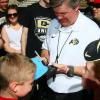 Coach Mike MacIntyre autographs a fan's hat