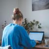 girl sits at desk inside and works on a computer
