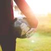 Woman standing in field with globe in hand