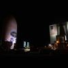 Satellite labeled "GOES" sits next to a large hangar labeled "NASA" at night time