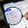 person holding a magnifying glass up to Google Drive screen on laptop