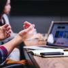 Employees sit at a conference table with laptops