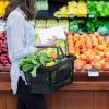 Person grocery shopping for produce with paper list in hand