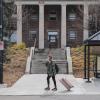 student with rolling suitcase departing campus for break
