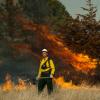 A man stand near a prescribed burn.