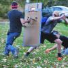 Human player blocks zombie players using cardboard shield